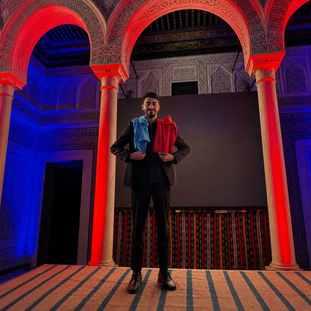 Dhia on stage under lit arches before a moderated evening session